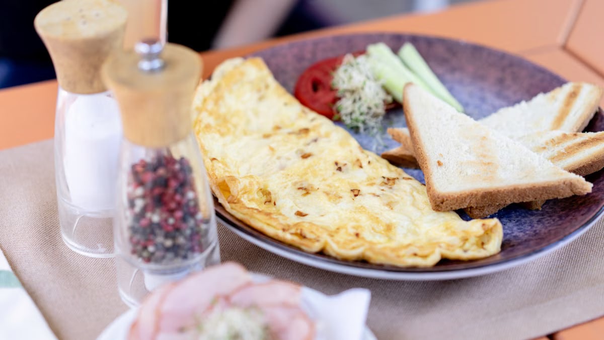 A nicely plated omelette breakfast with toast, cucumbers, and spices. Perfect start to the day.