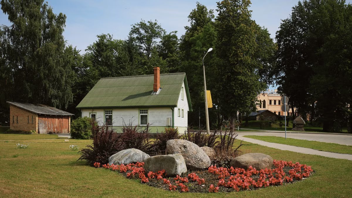 Picturesque house with flower bed in a serene rural setting, ideal for rustic lifestyles.